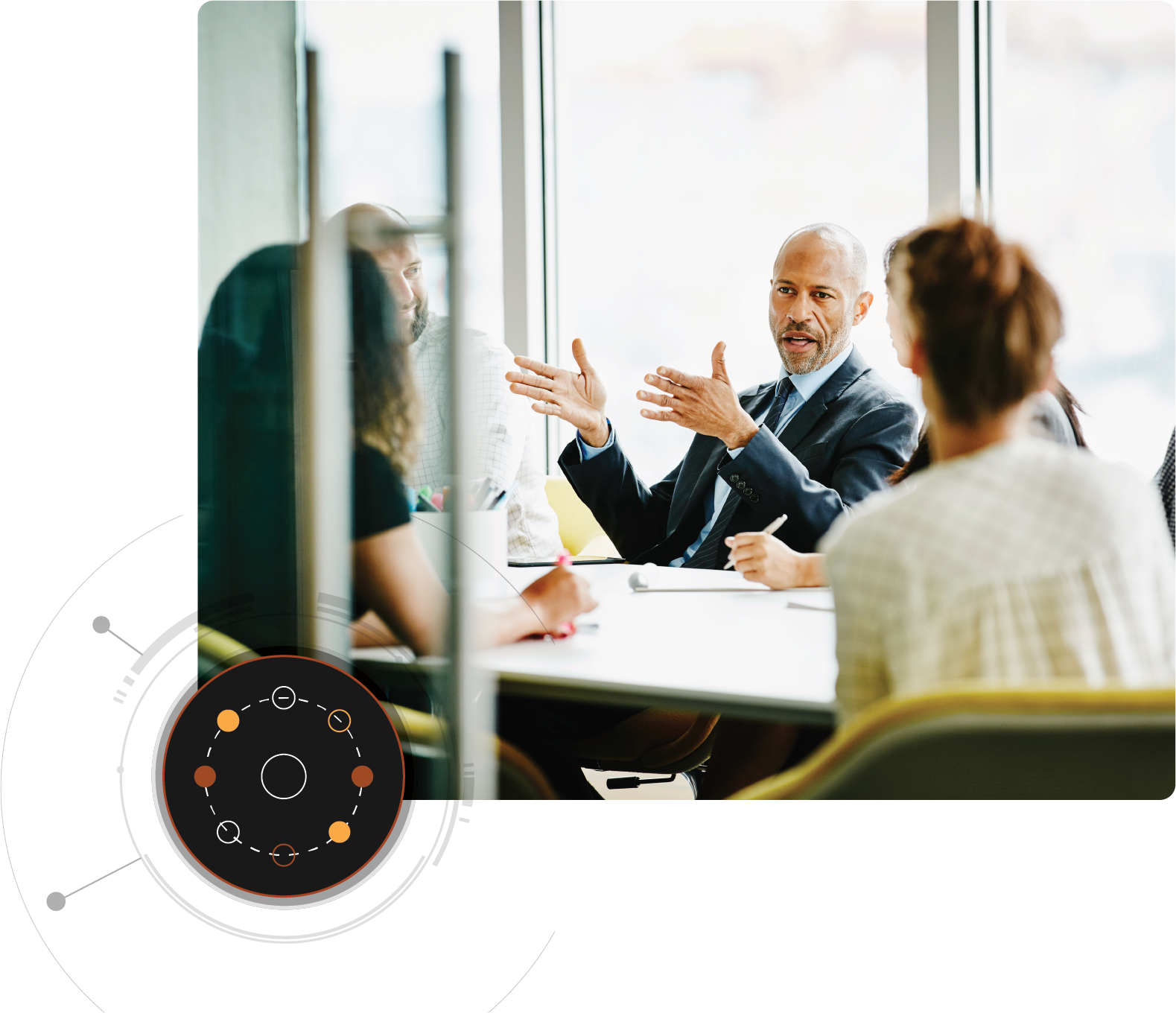 Ein Mann spricht mit mehreren Personen, die an einem Konferenztisch sitzen. Runde Overlaygrafik unten links.